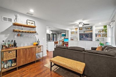 Living room with hardwood / wood-style floors, a wealth of natural light, ceiling fan, and bar | Image 3