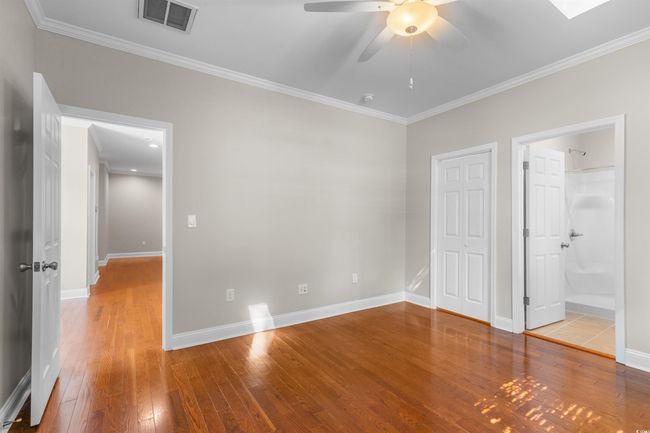 Unfurnished bedroom featuring wood-type flooring, ornamental molding, baseboards, ceiling fan, and ensuite bath | Image 15