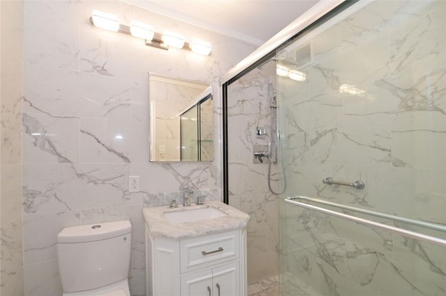 Bathroom featuring a marble finish shower, vanity, toilet, and tile walls | Image 9