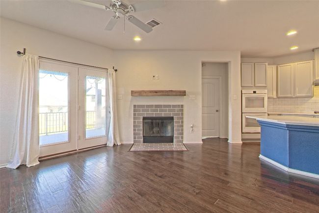 Unfurnished living room featuring ceiling fan, dark wood finished floors, a brick fireplace, and recessed lighting | Image 12