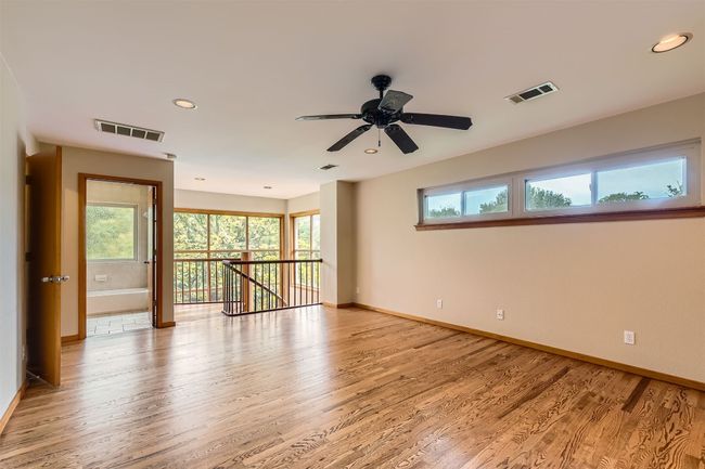 Large game room up with wood flooring, ceiling fan , spiral staircase going down to solarium | Image 19