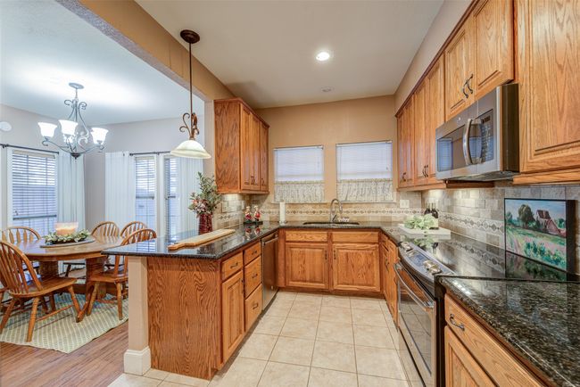 Kitchen with stainless steel appliances, brown cabinetry, and decorative backsplash | Image 12