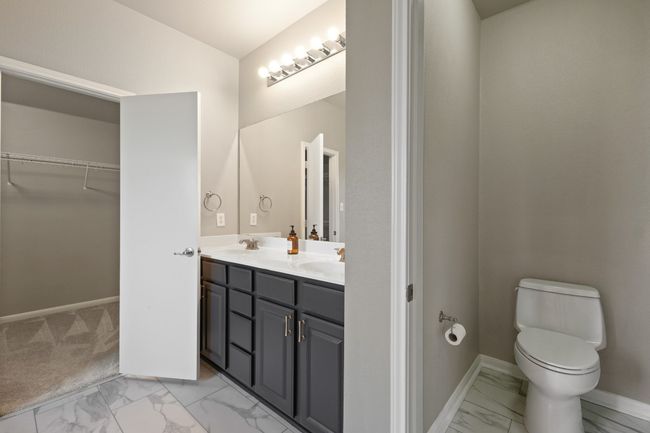 Full bathroom featuring marble look tiles, double vanity, toilet, a spacious closet, and baseboards | Image 19