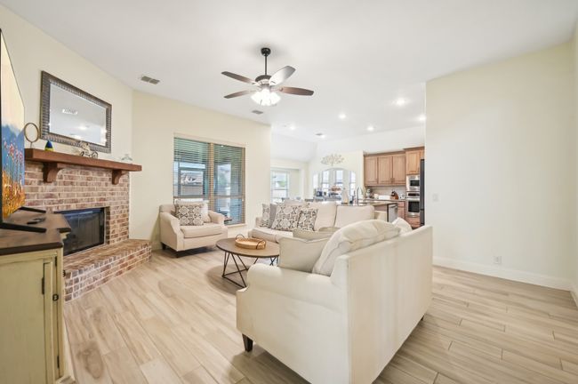 Living area featuring ceiling fan, a fireplace, light wood-style flooring, visible vents, and baseboards | Image 7