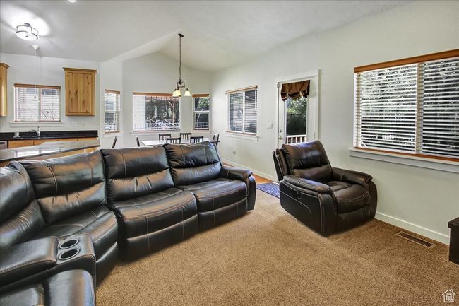 Carpeted living room featuring baseboards, vaulted ceiling, visible vents, and a sink | Image 10