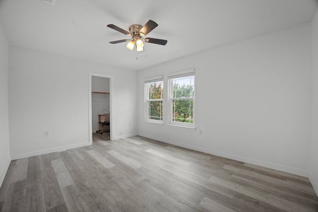 Unfurnished bedroom with wood finished floors, a spacious closet, a ceiling fan, a closet, and a desk | Image 19