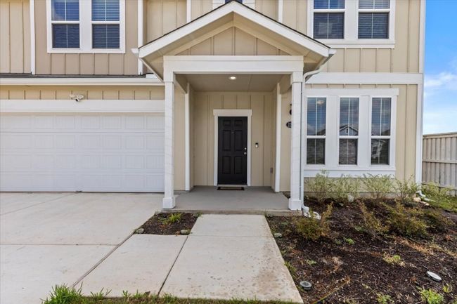 View of exterior entry with board and batten siding, driveway, and a garage | Image 4