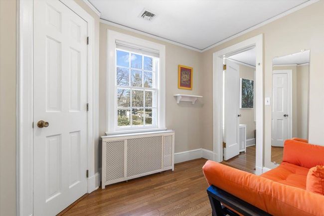 Sitting room with baseboards, visible vents, radiator, ornamental molding, and wood finished floors | Image 20