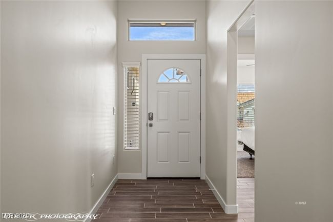 Foyer featuring dark wood-type flooring, baseboards, and a high ceiling | Image 9