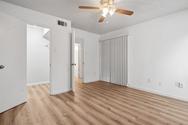 Unfurnished bedroom with visible vents, baseboards, a walk in closet, light wood-type flooring, and a textured ceiling | Image 12