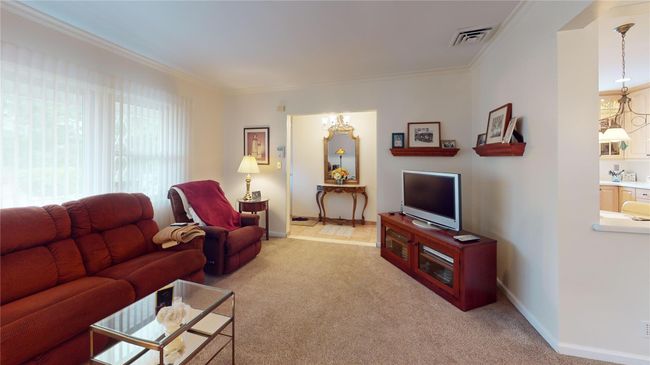 Living area featuring crown molding, light carpet, and a chandelier | Image 4