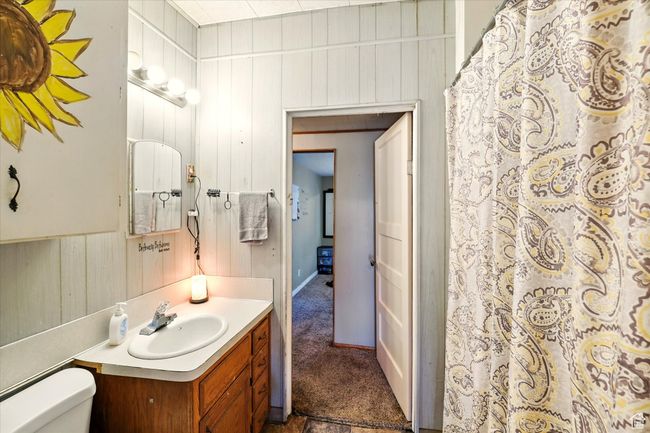 Full bath featuring vanity, toilet, wood walls, and a shower with shower curtain | Image 10