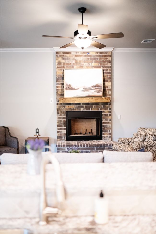 Living area featuring a fireplace, visible vents, crown molding, and a ceiling fan | Image 5