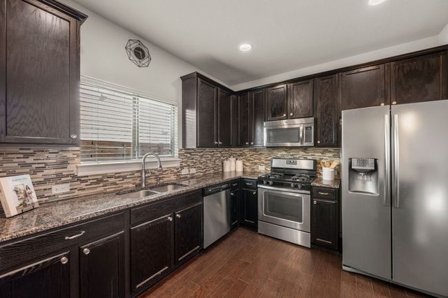 Kitchen with appliances with stainless steel finishes, a sink, and dark stone countertops | Image 15