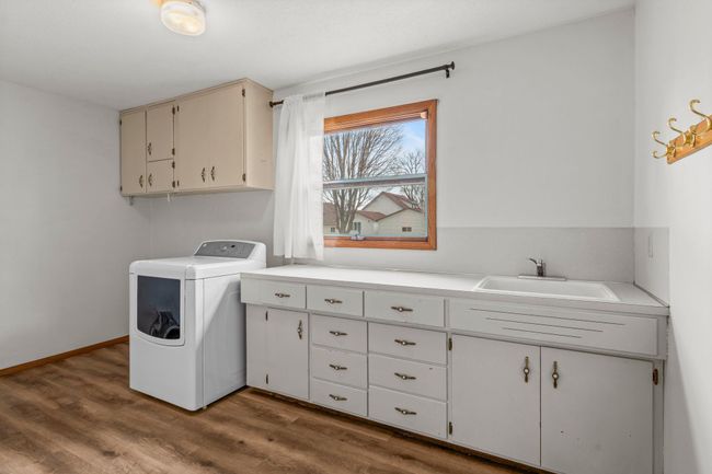 The main-level laundry room offers ample counter space, a utility sink and cabinetry, providing convenience and efficiency to simplify laundry day. | Image 9