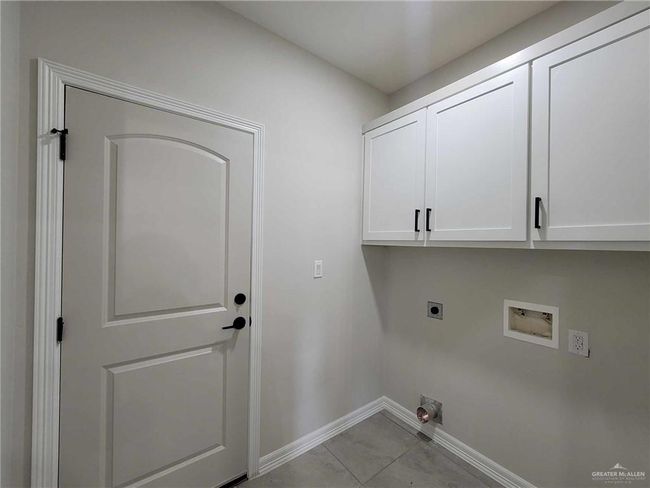 Clothes washing area featuring washer hookup, light tile patterned flooring, cabinets, and hookup for an electric dryer | Image 18