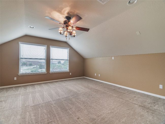Additional living space featuring a ceiling fan, lofted ceiling, healthy amount of natural light, and carpet | Image 36