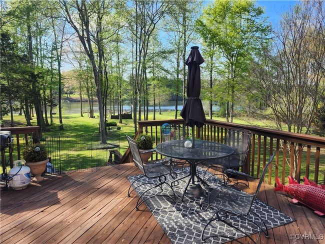 Wooden deck with a yard, outdoor dining space, and a water view | Image 23
