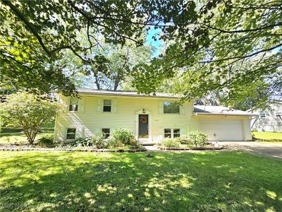 Bi-level home featuring a garage and a front lawn | Image 1