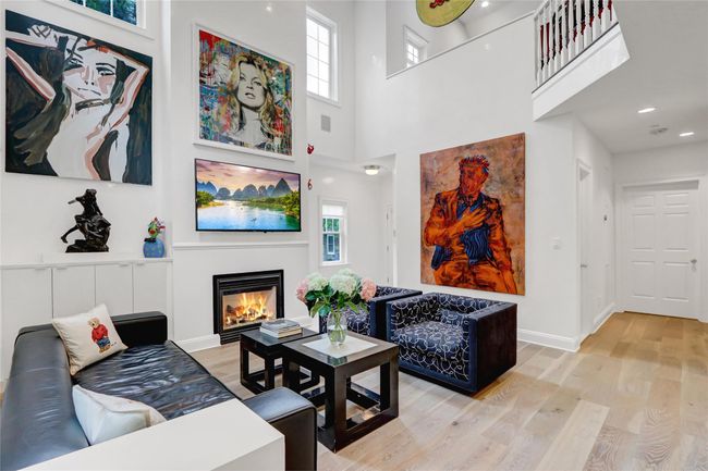 Living room featuring wood finished floors, a glass covered fireplace, a towering ceiling, and recessed lighting | Image 6