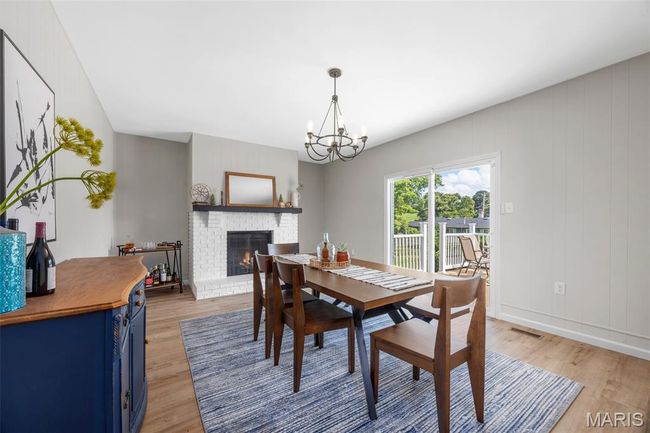 Dining space with light LVP flooring, a brick fireplace, and a chandelier | Image 15
