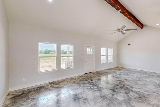 Unfurnished living room featuring baseboards, vaulted ceiling with beams, and a ceiling fan | Image 7
