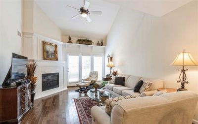 Living room with ceiling fan, a fireplace, dark hardwood / wood-style floors, and high vaulted ceiling | Image 3