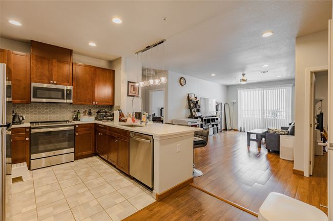Kitchen with appliances with stainless steel finishes, a peninsula, open floor plan, backsplash, and light countertops | Image 14