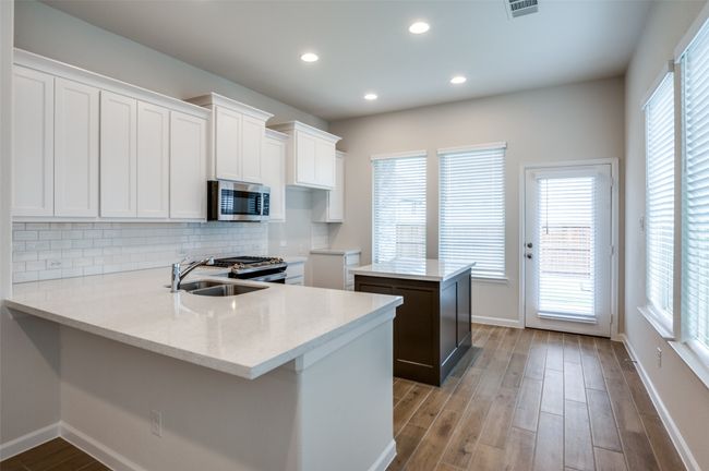 Kitchen with white cabinetry, sink, stainless steel appliances, a kitchen island, and light wood-type flooring | Image 11