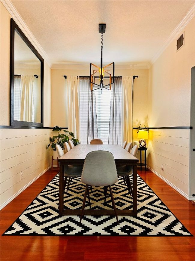 Dining room with a notable chandelier, ornamental molding, wood walls, visible vents, and wood finished floors | Image 7