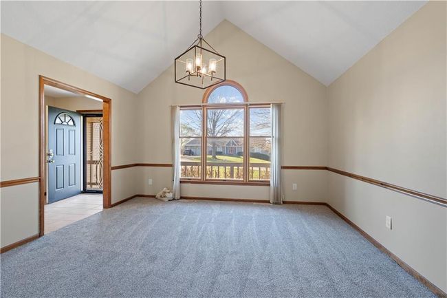 Carpeted spare room featuring a chandelier, baseboards, and high vaulted ceiling | Image 5