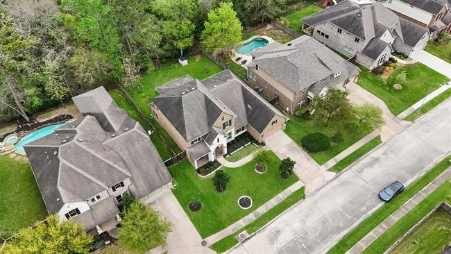 This beautiful aerial view highlights a well-maintained two-story home backing to a serene greenbelt with no rear neighbors. Enjoy added privacy, a spacious yard, and a welcoming presence on a quiet, tree-lined street. | Image 42