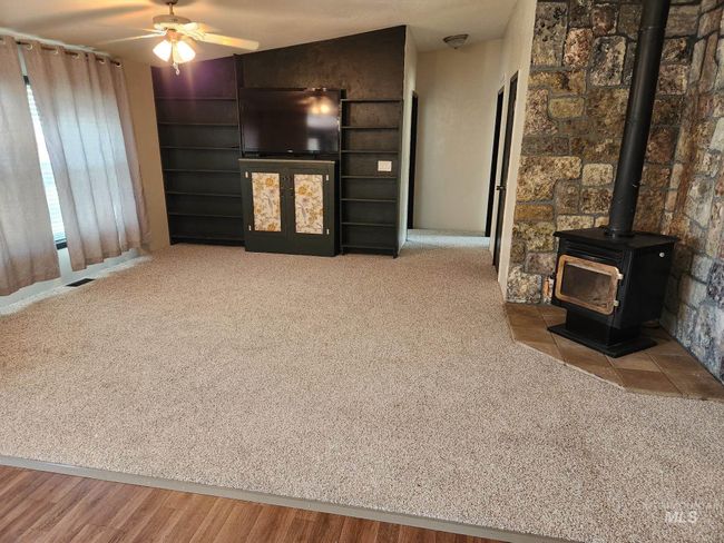 Unfurnished living room with carpet floors, a ceiling fan, and a wood stove | Image 4