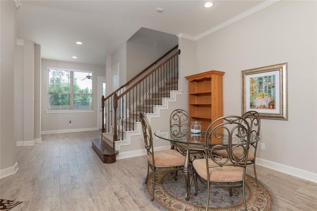 This inviting home features a bright entryway with wood-like flooring and a staircase with elegant railings. An open dining area, creating a cozy yet sophisticated atmosphere. Large windows provide plenty of natural light. | Image 21