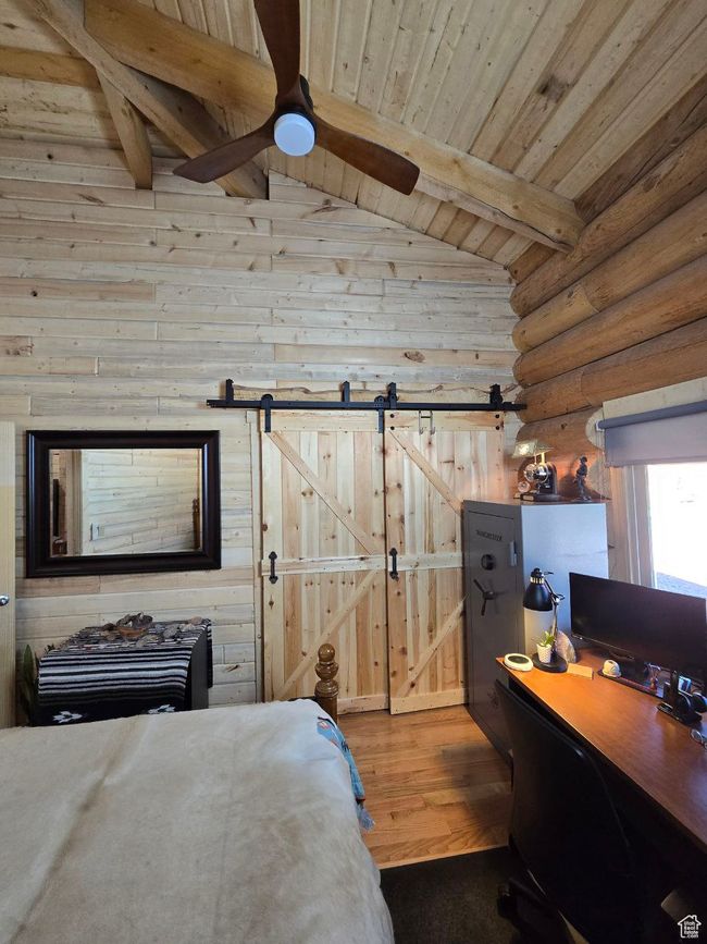 Bedroom featuring wood finished floors, vaulted ceiling with beams, a barn door, wooden ceiling, and rustic walls | Image 88