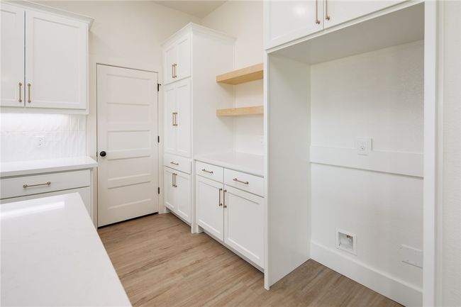 Kitchen with light wood-style floors, light countertops, and white cabinetry | Image 13