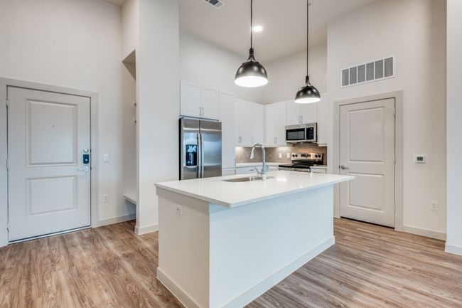 Kitchen with visible vents, a center island with sink, a high ceiling, stainless steel appliances, and a sink | Image 19