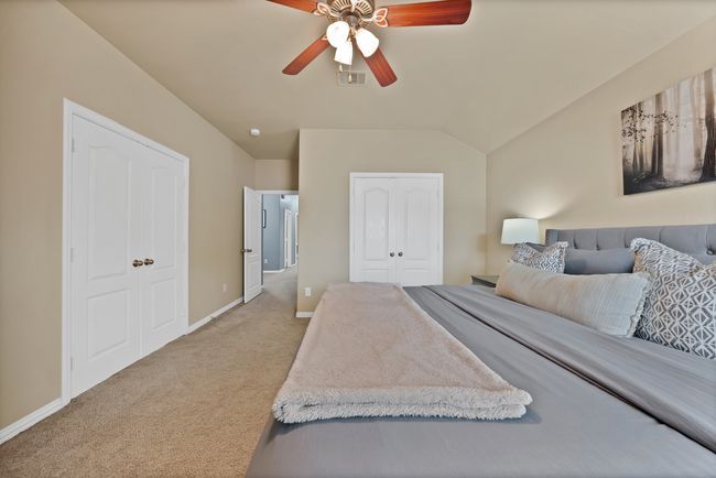Bedroom with light colored carpet, lofted ceiling, baseboards, a closet, and ceiling fan | Image 32
