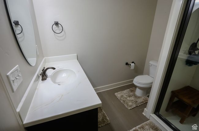 Bathroom featuring vanity, toilet, a shower stall, wood finished floors, and baseboards | Image 56
