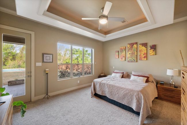 Primary bedroom featuring a lighted raised decorative ceiling with multiple windows looking out at pool and back yard | Image 14