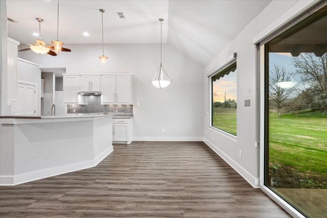 Kitchen featuring dark hardwood / wood-style flooring, backsplash, vaulted ceiling, decorative light fixtures, and white cabinetry | Image 33