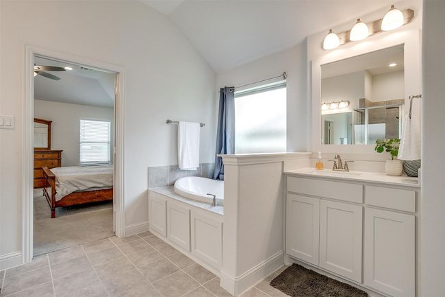 Full bathroom featuring lofted ceiling, a shower stall, a bath, vanity, and a ceiling fan | Image 24