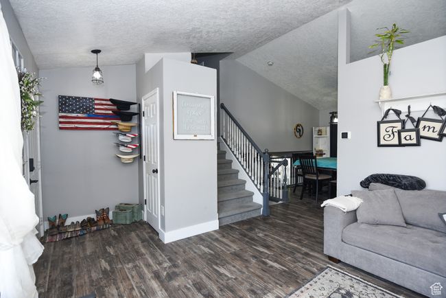 Living area with a textured ceiling, lofted ceiling, wood finished floors, and baseboards | Image 11