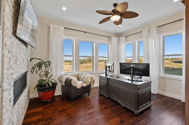 Tucked away for quiet work, this office shares the double-sided fireplace with the great room and features custom built-ins and a warm, inviting atmosphere. | Image 11