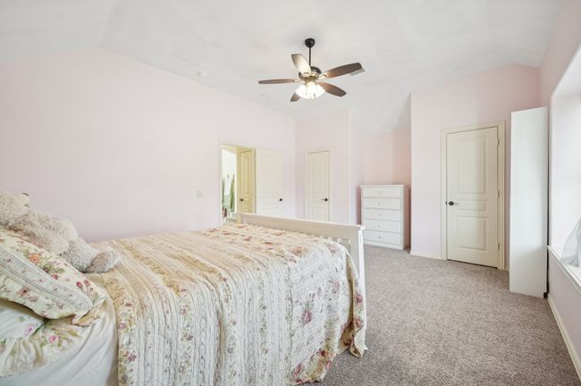 Bedroom featuring ceiling fan, light colored carpet, and vaulted ceiling | Image 32