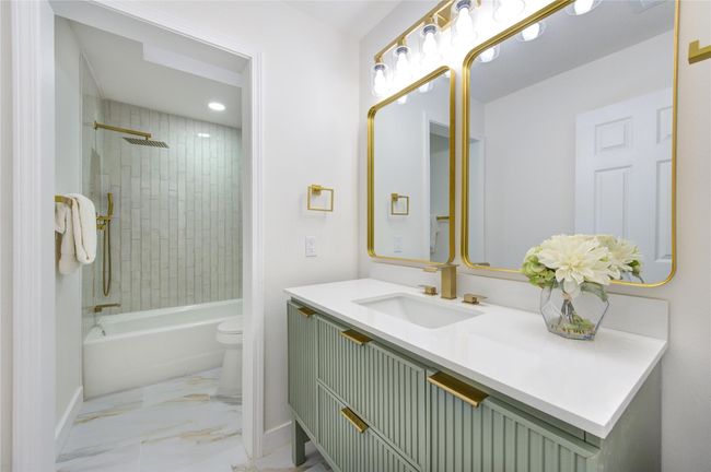 The secondary bathroom has been completely updated with new tile, a modern vanity, and Quartz countertops. A shower/tub combo with updated fixtures offers functionality while maintaining the home’s fresh and modern aesthetic. | Image 23