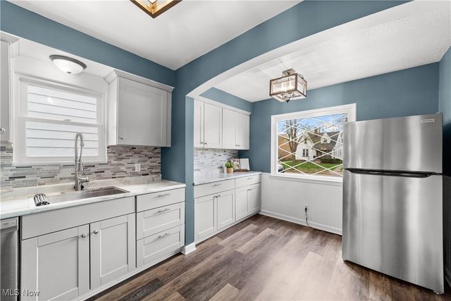 Kitchen with decorative backsplash, appliances with stainless steel finishes, light countertops, a sink, and dark wood-type flooring | Image 9