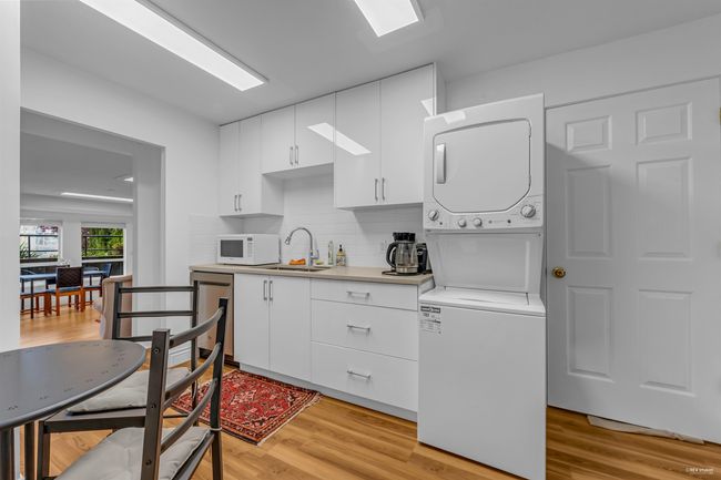 Kitchen with estacked washer and dryer, dishwasher, a sink, white microwave, and light countertops | Image 31
