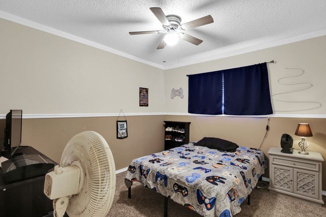 Carpeted bedroom featuring a textured ceiling, ceiling fan, and ornamental molding | Image 8
