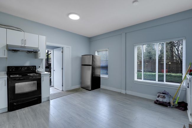 Kitchen featuring freestanding refrigerator, under cabinet range hood, light countertops, white cabinets, and black electric range | Image 28